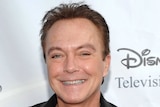 Actor-singer David Cassidy smiling on the red carpet with a Disney sign behind him