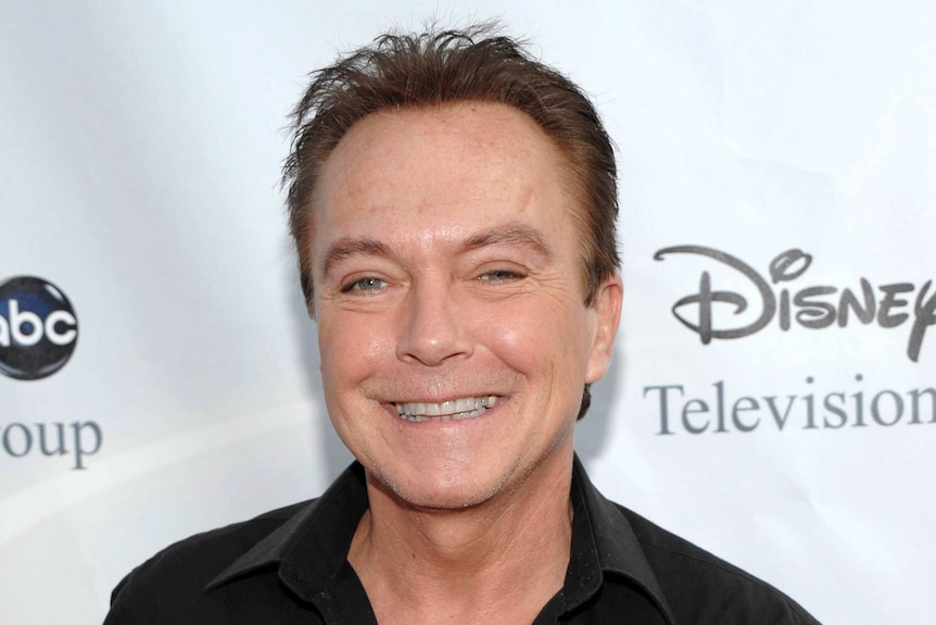 Actor-singer David Cassidy smiling on the red carpet with a Disney sign behind him