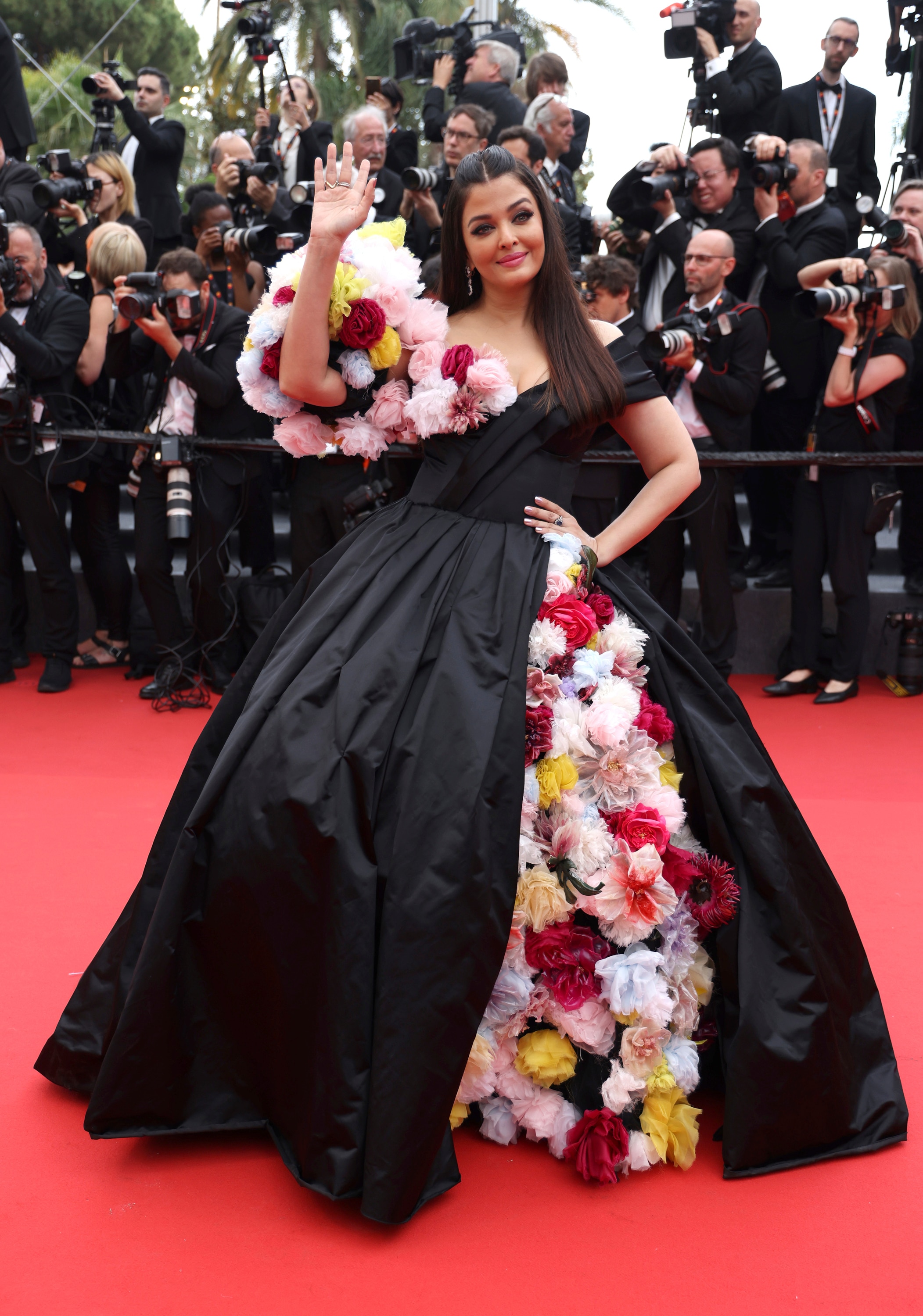 艾西瓦娅·雷·巴强 (Aishwarya Rai Bachchan) 身穿黑色蓬松长裙，薄纱花朵从裙子的开衩处垂落，形成袖子