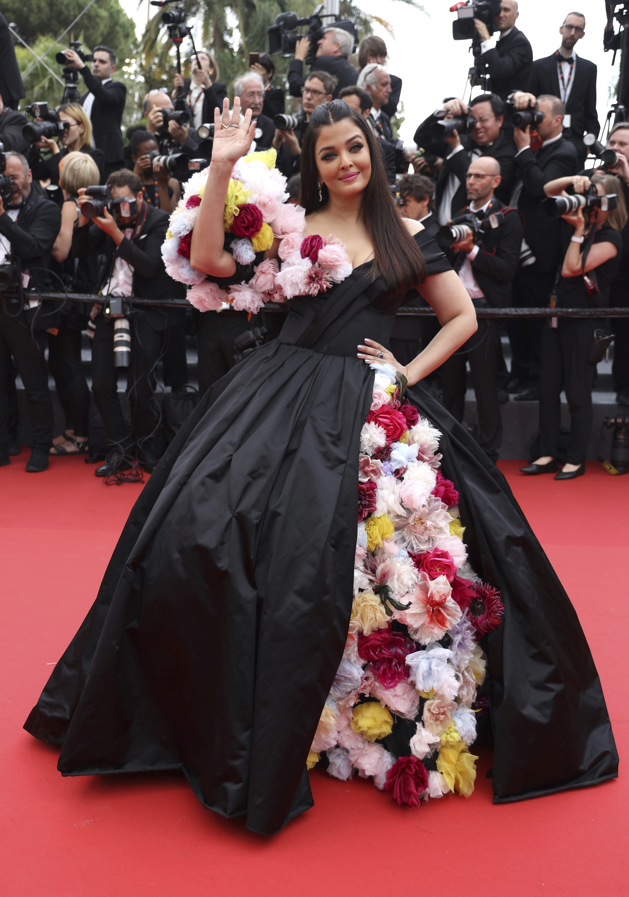 艾西瓦娅·雷·巴强 (Aishwarya Rai Bachchan) 身穿黑色蓬松长裙，薄纱花朵从裙子的开衩处垂落，形成袖子