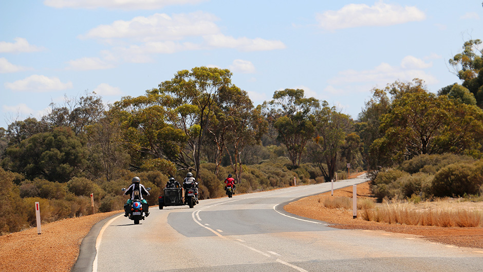 The Barker family rides off into the distance on three bikes with bushland surrounding the road.