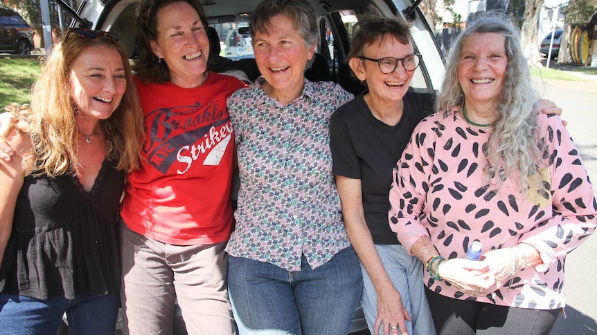 Five women sit in the boot of a car after bumping out their sound equipment.