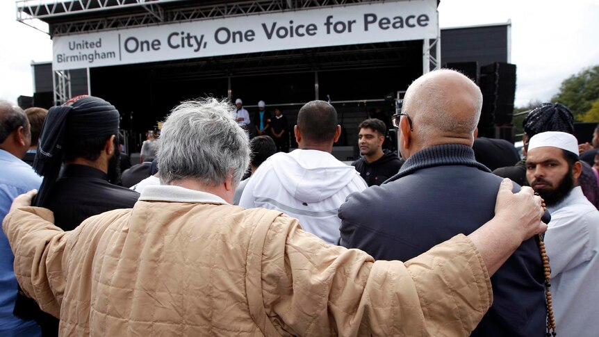 People embrace at peace rally in Birmingham after three were killed as they guarded against looters