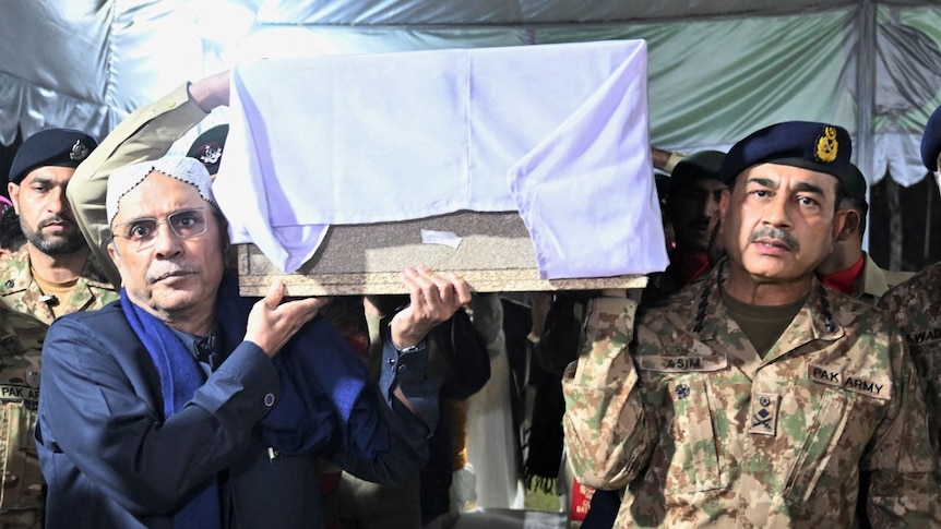 Two men in military uniform carry a coffin draped in a white sheet