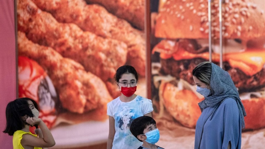An Iranian woman and children stand in front of a fast food store in Tehran.