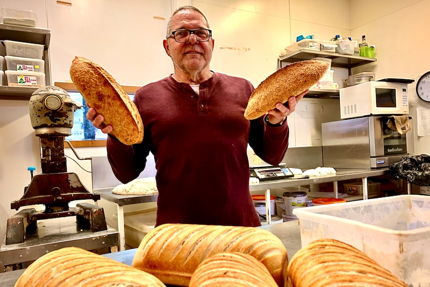 Man standing in kitchen with loaves of bread