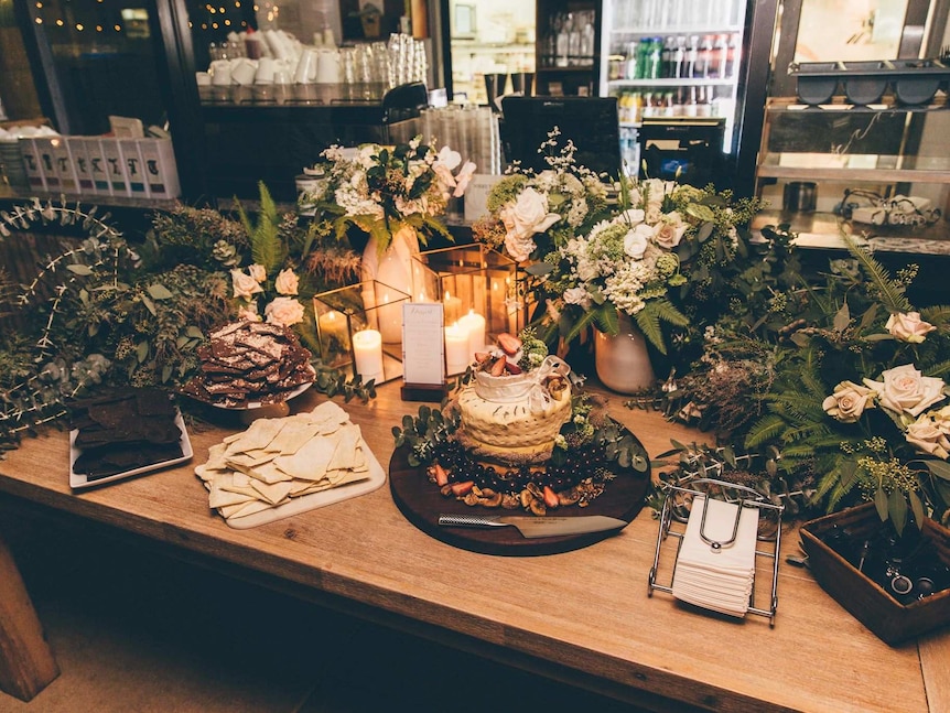 A table covered in flowers and a plate with several different types of cheese layered on top of each other