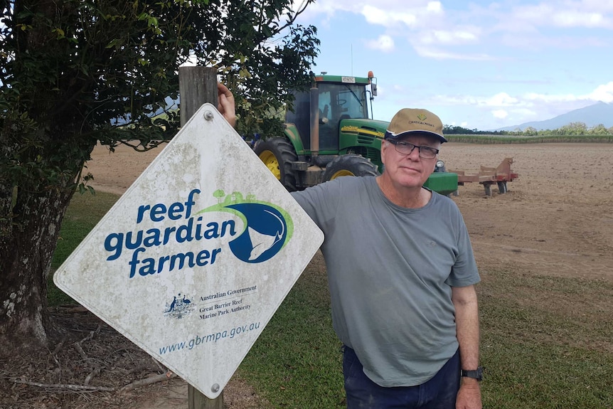 Paul Gregory stands next to a sign saying 'reef guardian farmer'.