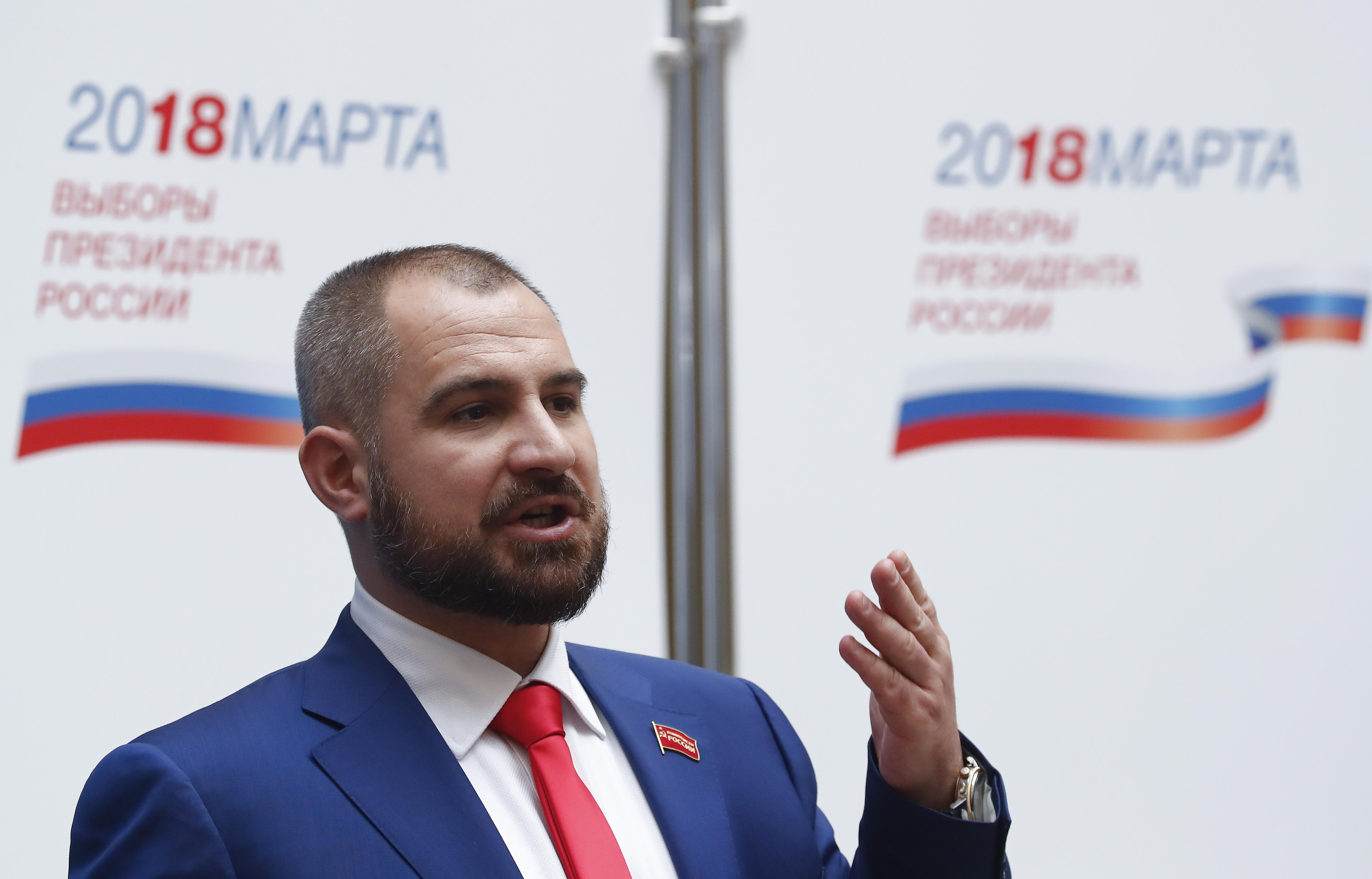 A man in a blue suit and red tie speaks 