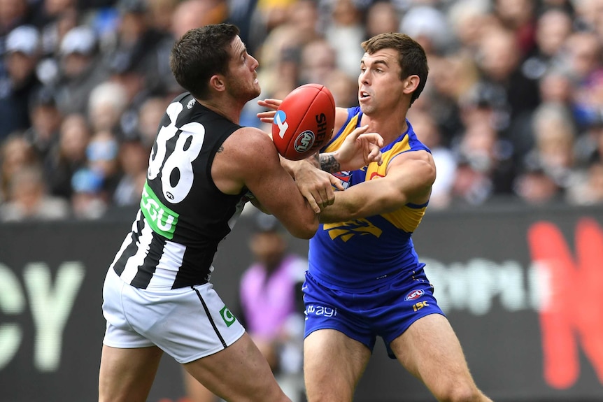 Two men grapple with each other with the ball between them