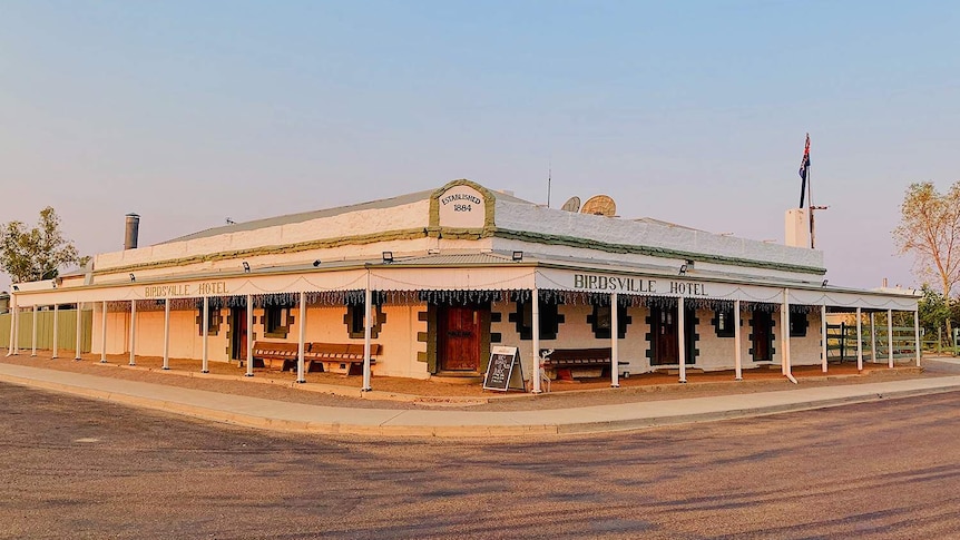 A large outback pub at a crossroads in a dusty town.