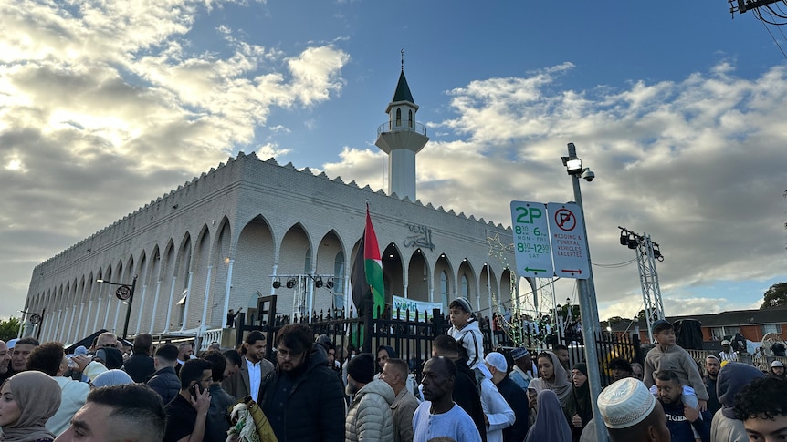 Hundreds of Muslims outside Lakemba mosque, with the Palestinian flag flying on the front gate.