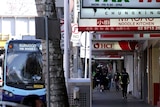 A bus departs from a stop outside shops on Burwood Road.