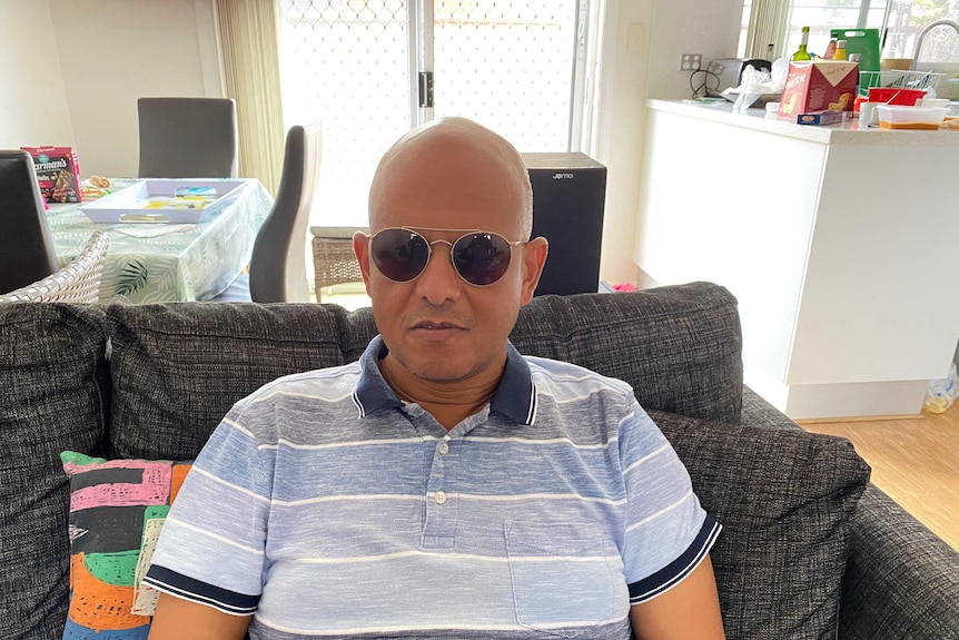 Gideon Kibret sits on his couch wearing sunglasses