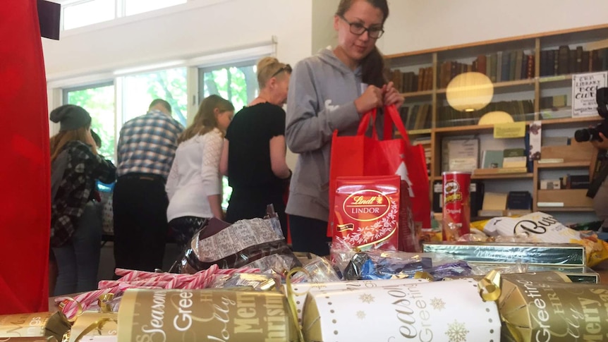 Volunteers pack lollies and chocolates into Christmas hampers for ex-prisoners.