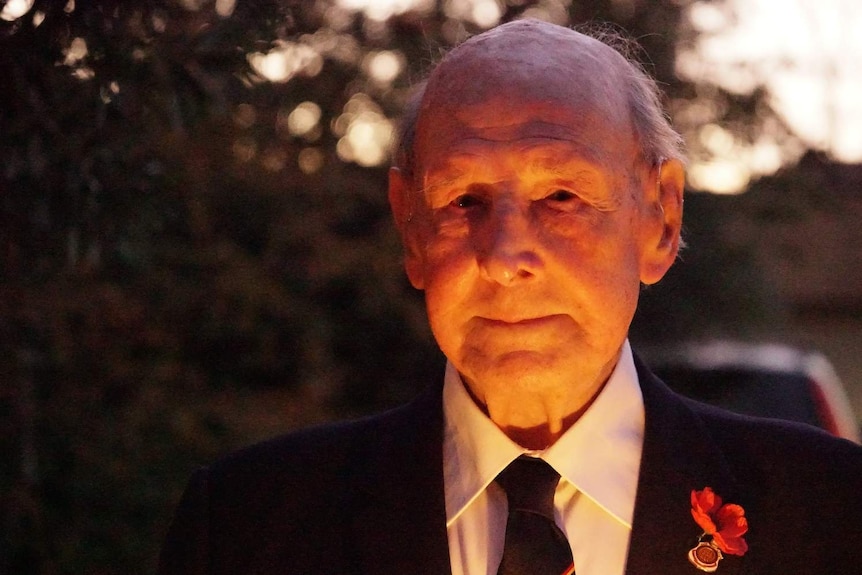 Frank Sims stands in his driveway holding a candle at dawn.