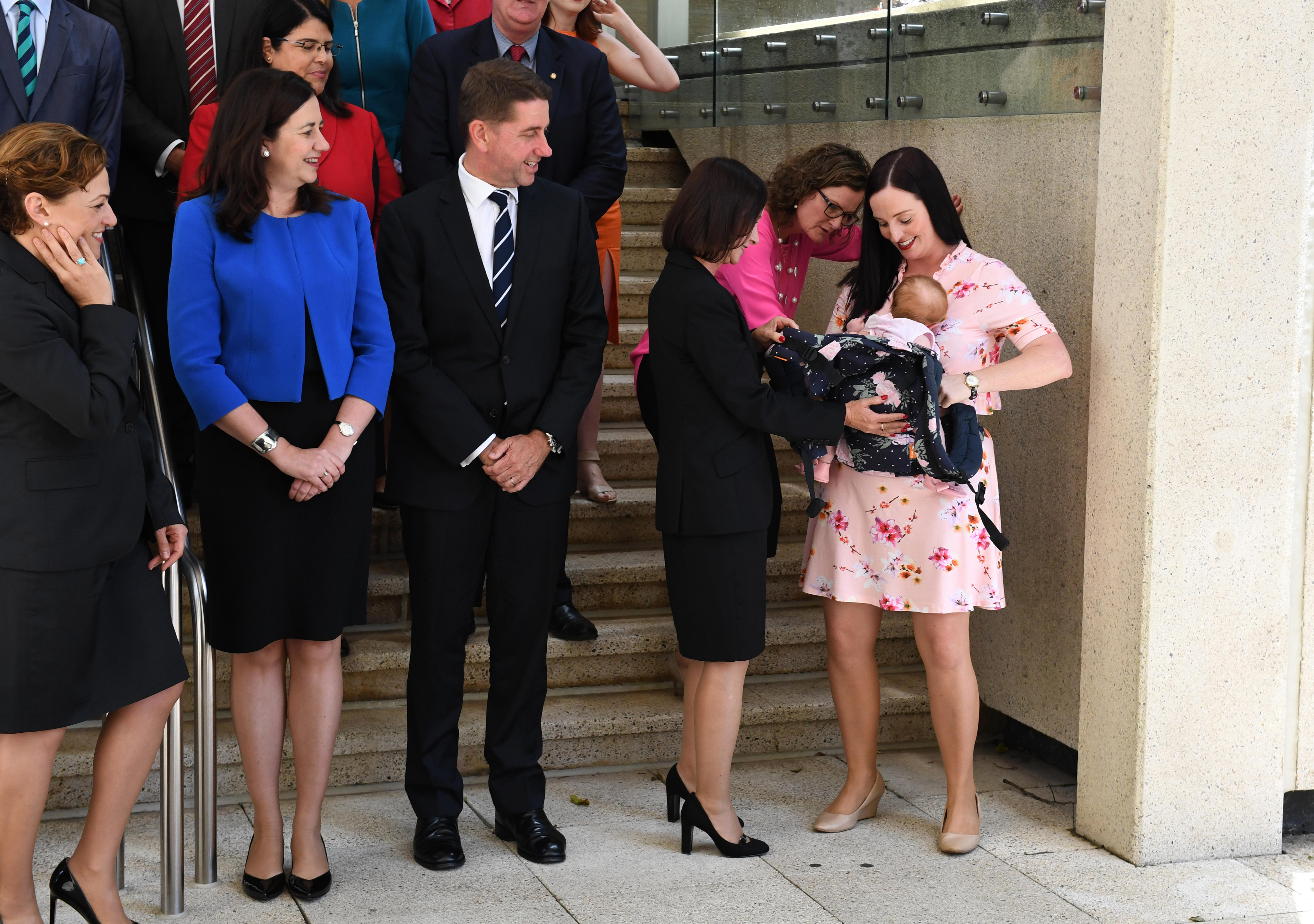 Brittany Lauga watched by Premier Annastacia Palaszczuk, adjusts her baby Odette's sling during a group photo 