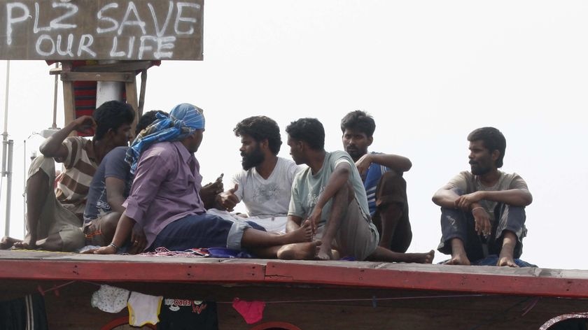 Detained Sri Lankan asylum seekers stand in their wooden boat in Cilegon harbour