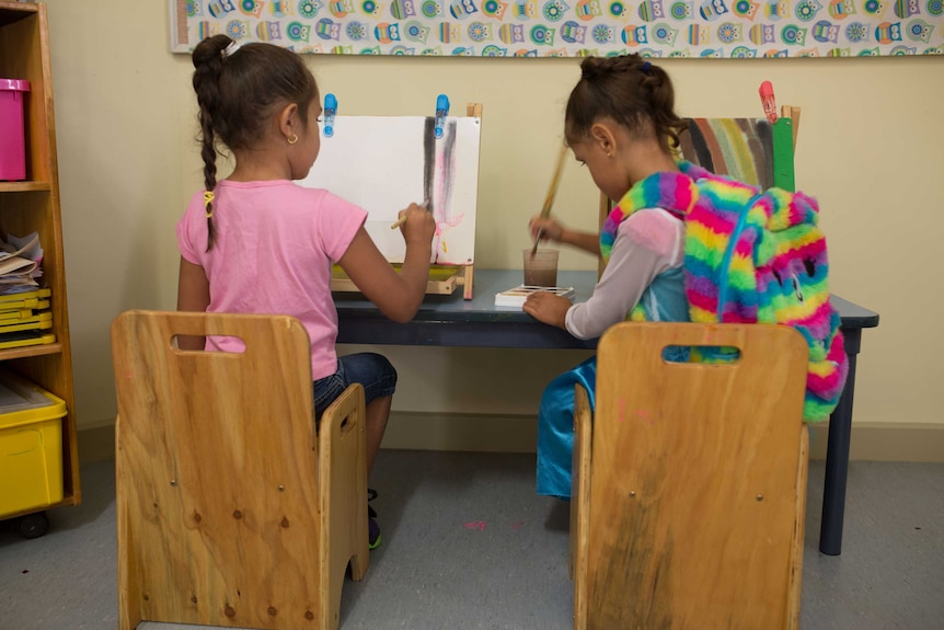 Two girls sitting down and painting during class at Lulla's.