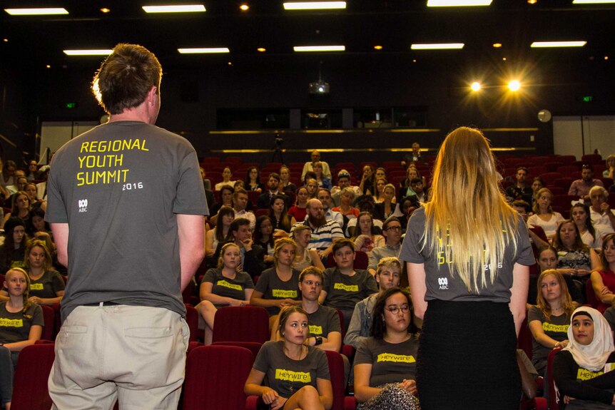 Two Heywire winners stand in front of an audience.