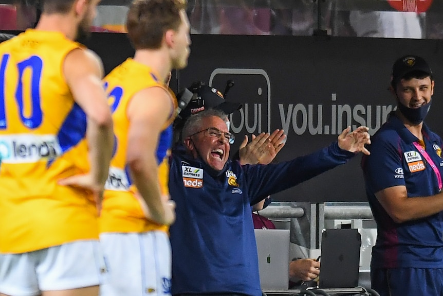 An AFL coach lets out a joyful roar at the end of the game as his team makes sure they finish fourth.