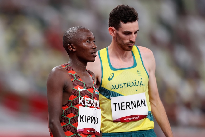 Two long distance runners stand next to each other before the start of a race.