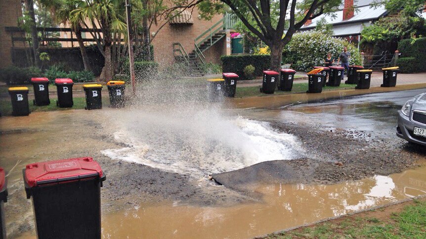 Water gushes from a Glenside street after a pipe burst