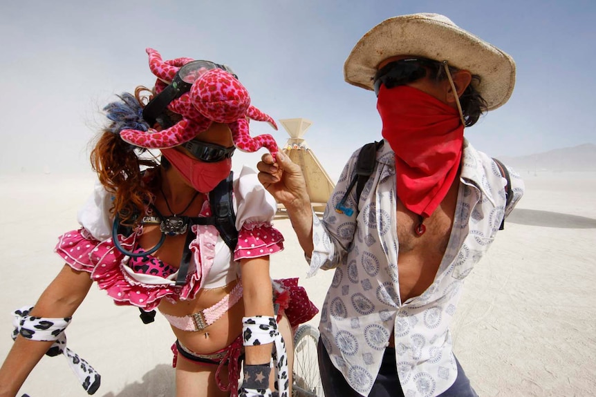 A participant shows her octopus hat to a friend as they visit the effigy of the man during the Burning Man festival