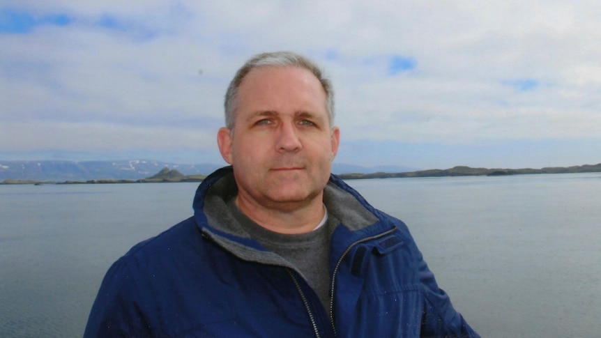 Paul Whelan in Iceland looking into the camera with a water landscape behind.