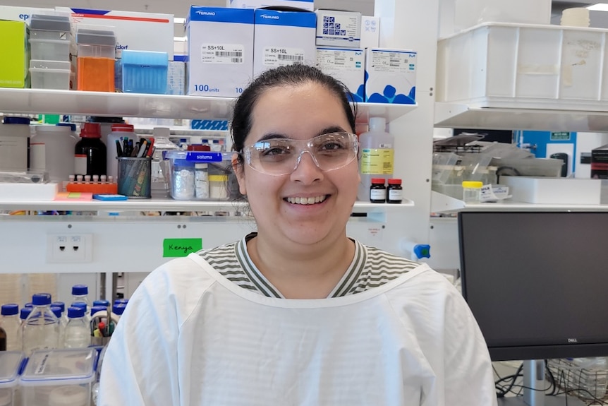 Kenya Fernandes wears plastic glasses and white gown in the lab.