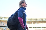 Will Ashcroft walks along the boundary at the Gabba carrying his gear