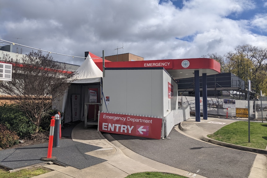 white tent at front of emergency department red signs