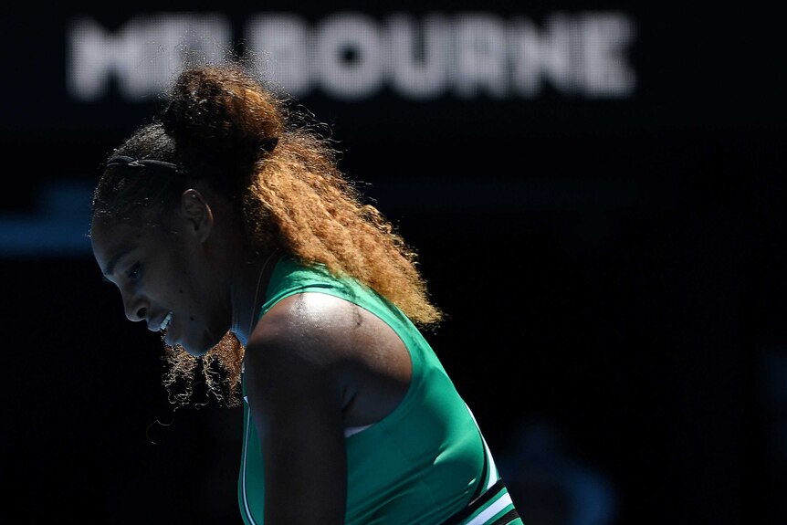 Serena Williams is seen in profile with a pained expression on her face while playing at the Australian Open.