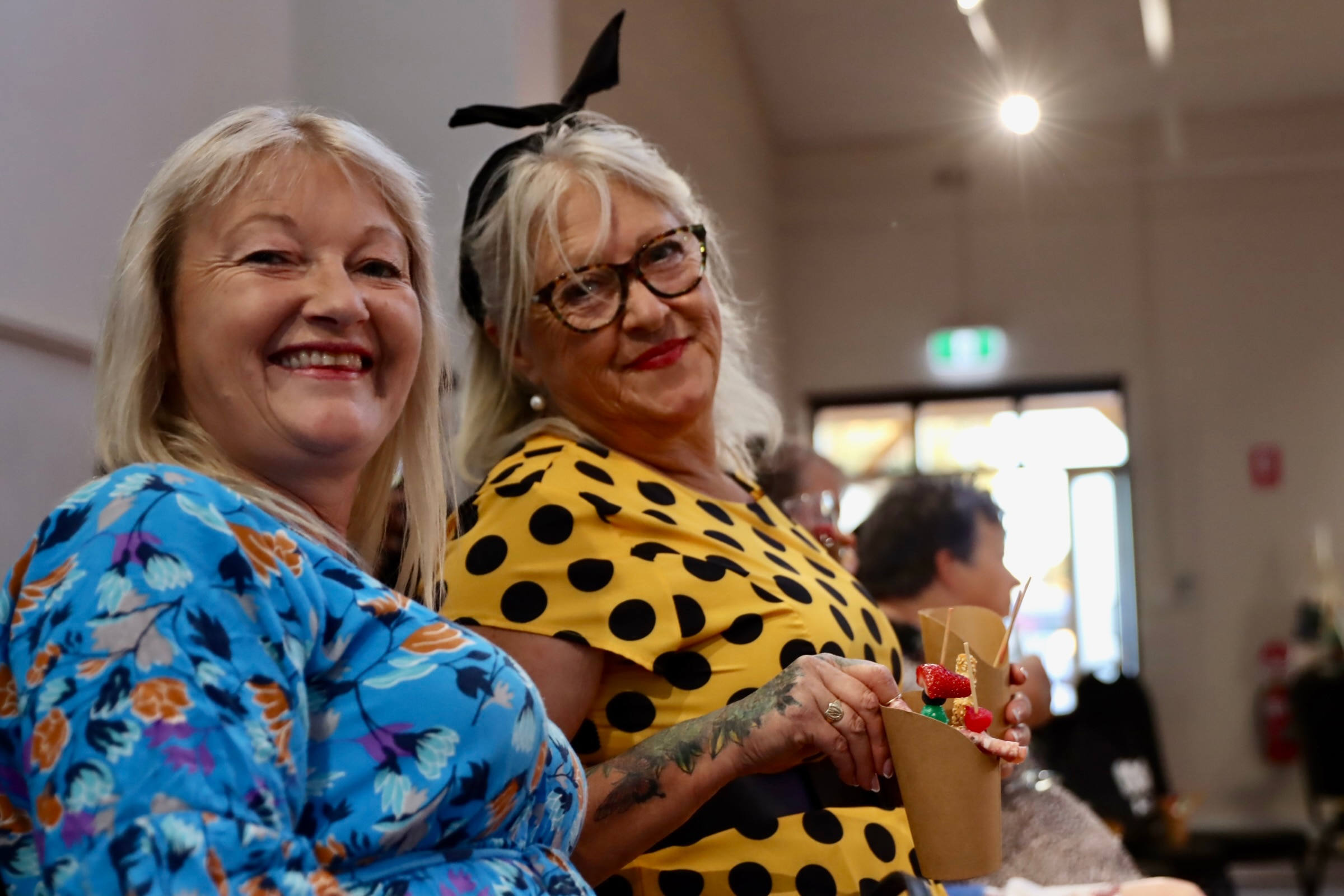 Two women wearing brightly patterned dresses.