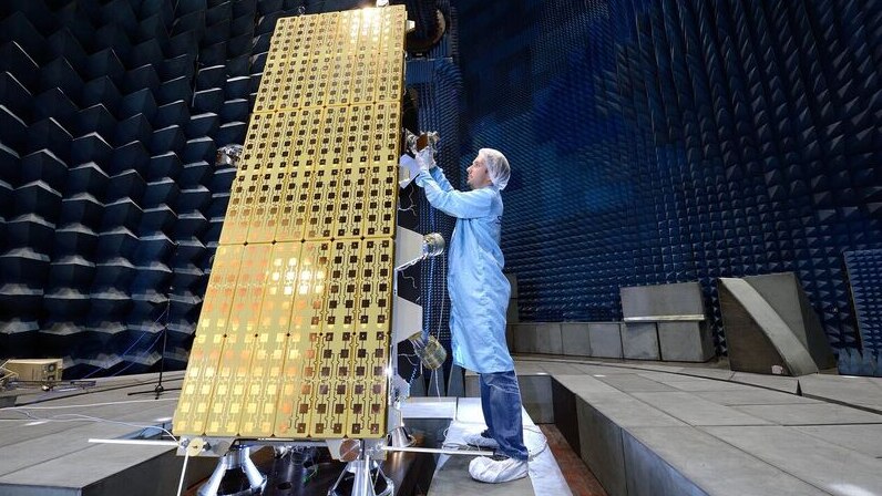 A man works on a satellite in a laboratory.
