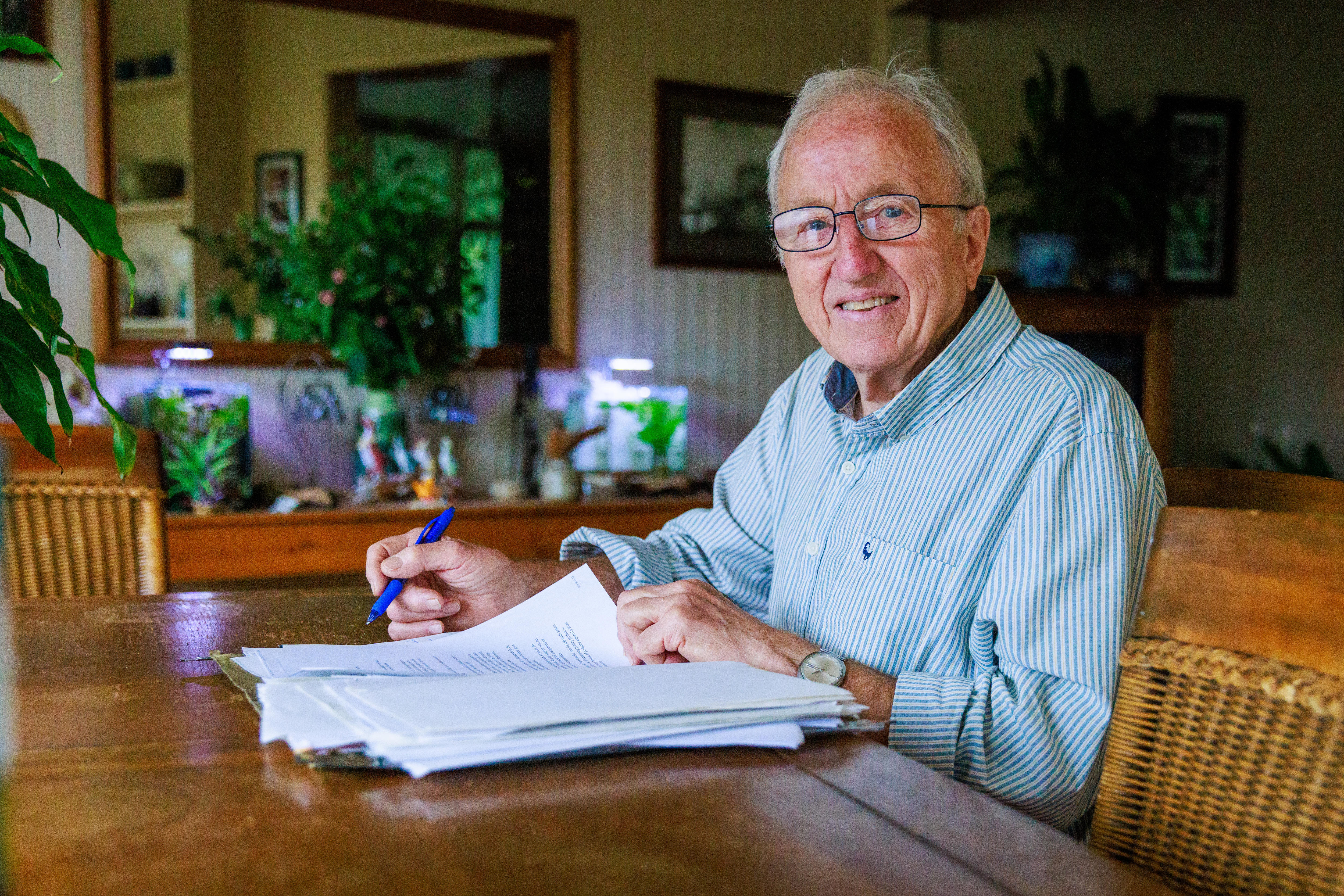 Keith Loveridge sits at a kitchen table, writing in a book.