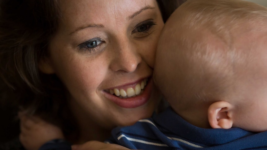 Close up shot of mother Kira Longfield smiling cuddling her baby William.
