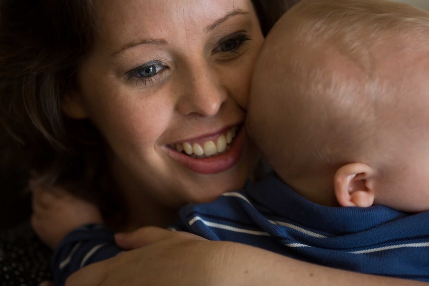 Close up shot of mother Kira Longfield smiling cuddling her baby William.