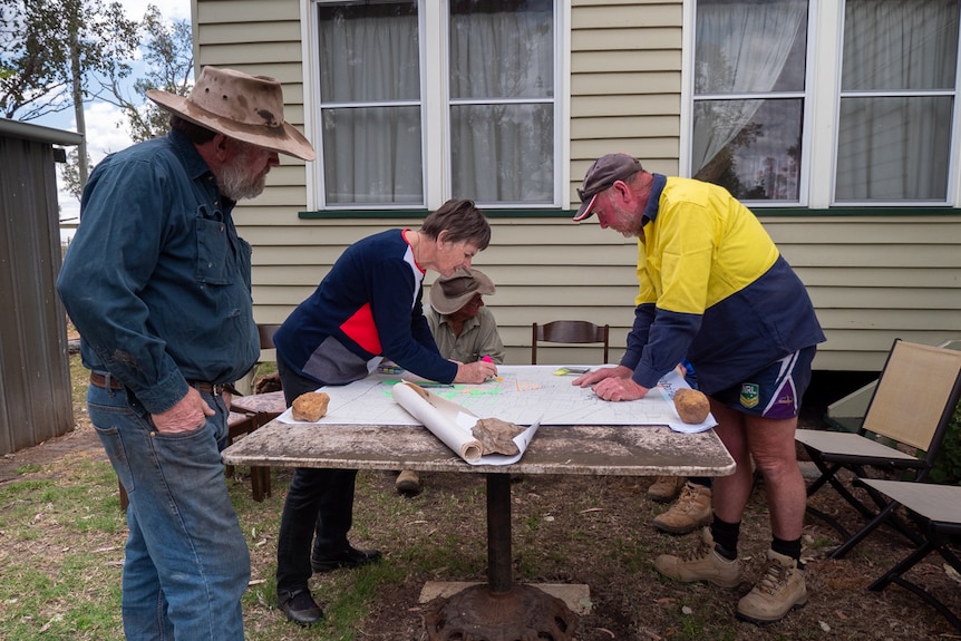 A group of farmers stand around a map looking at where the gas project is being proposed, October 2020.