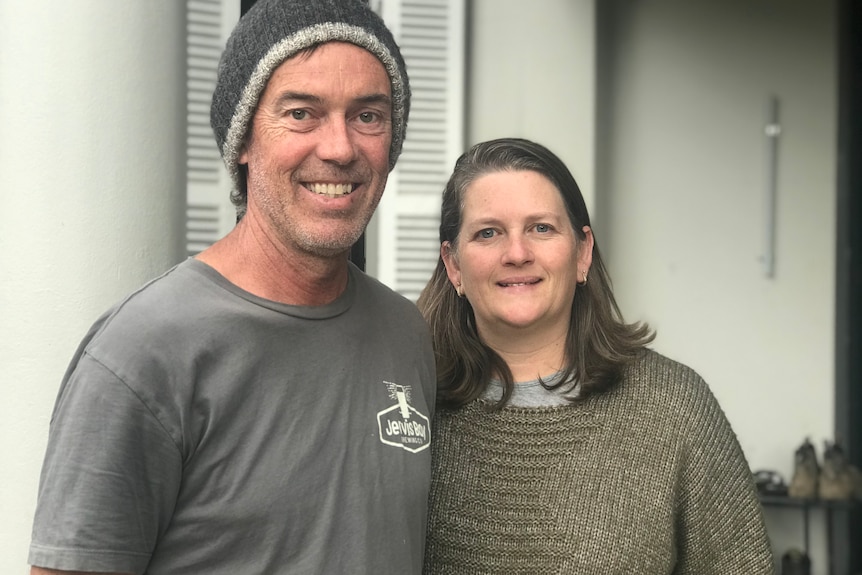 A married couple standing together with big smiles on their faces.