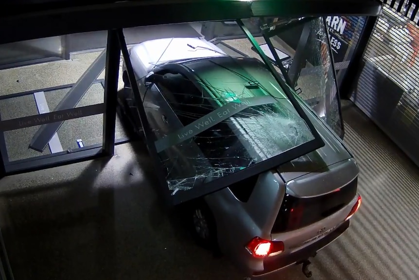 A four-wheel drive sits halfway through broken glass doors.