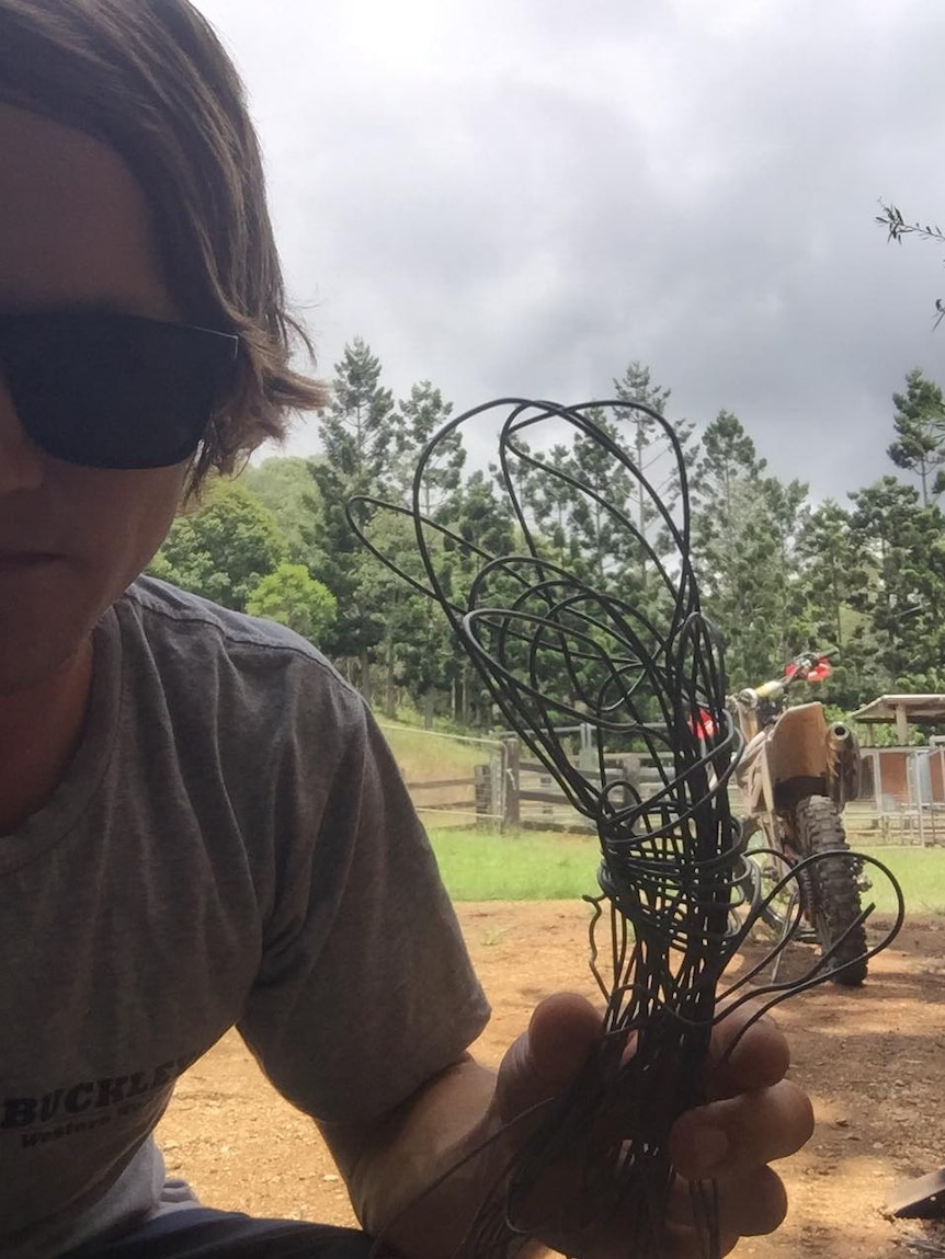 Man wearing sunglasses holding a bundle of metal wire