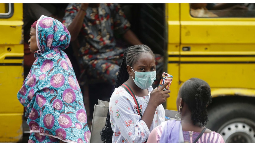 A woman wearing a face mask walks nearby the Central Mosque in Lagos, Nigeria.