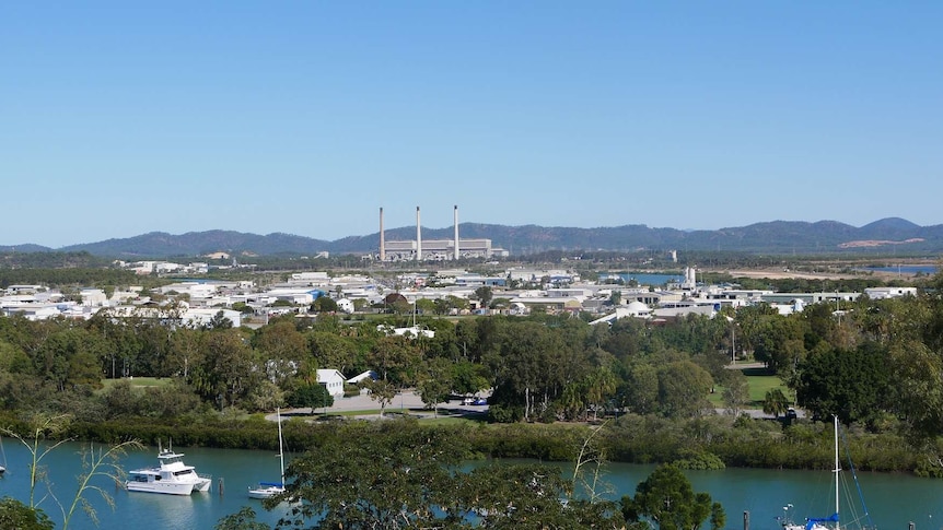 Blue sky over a marina and city with a power plant in the background