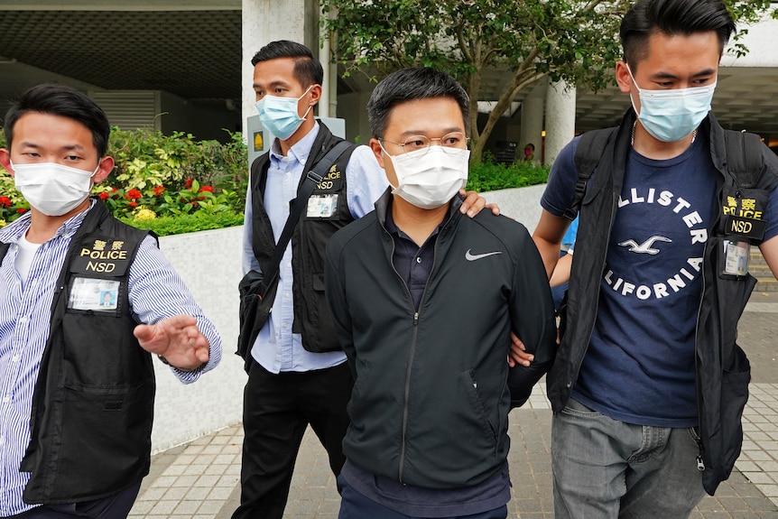 Ryan Law salió de la oficina de Apple Daily con los brazos a la espalda escoltado por los agentes de policía.