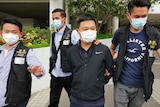 Ryan law being walked out of the Apple Daily office with arms behind his back escorted by the police officers.