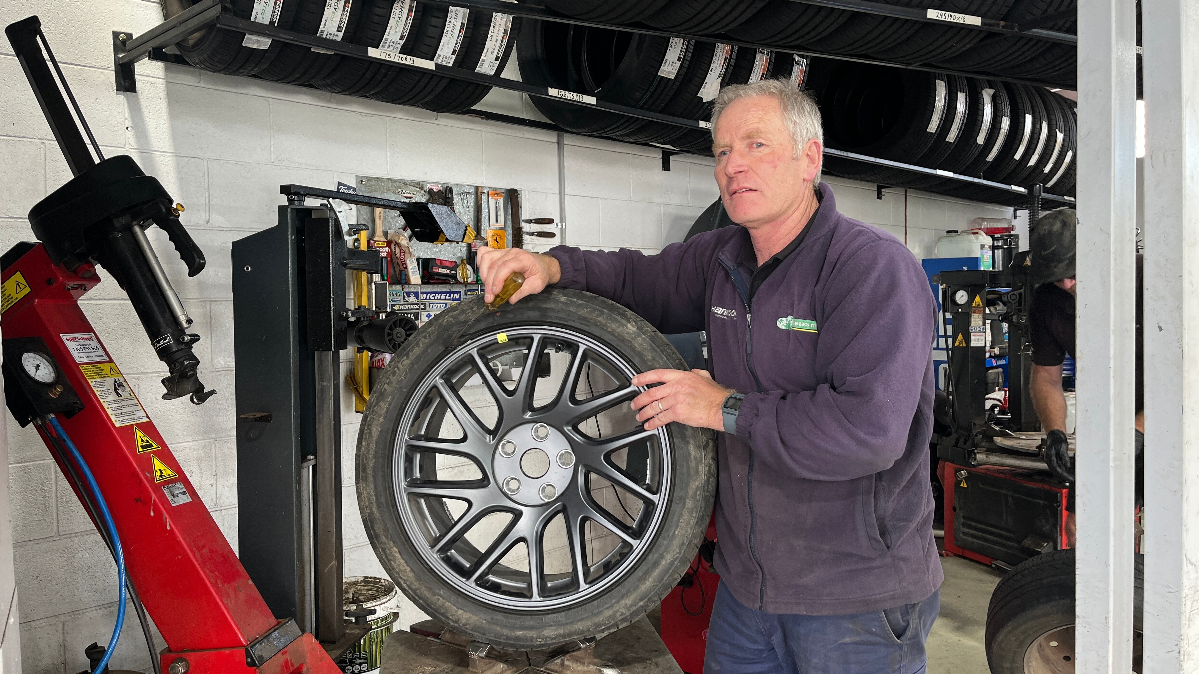 a man in a navy jumper stands in front of a tyre