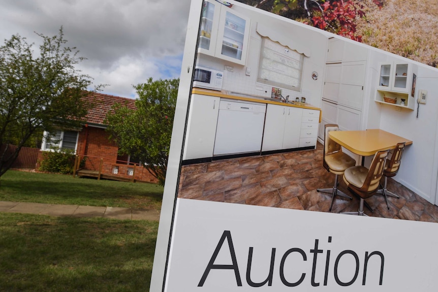 A real estate auction sign in front of a house.