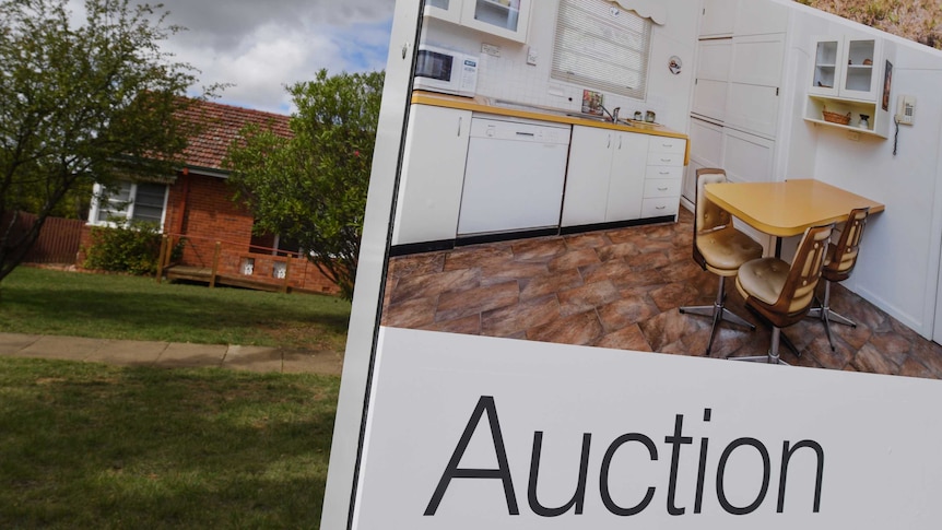 Auction sign in front of house with lawn and footpath
