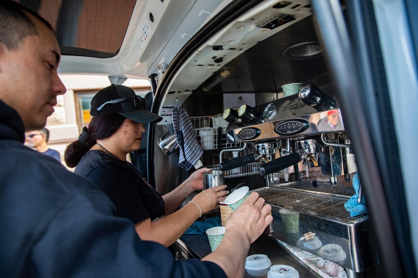Wide shot of Sunny making coffee at the back of the van.
